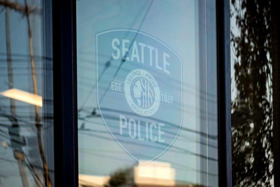 The Seattle Police emblem in the window of the East Precinct surrounded by reflections of the street. 